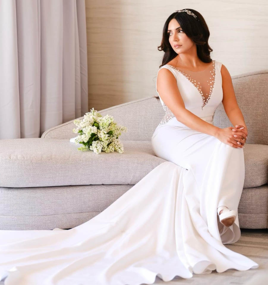 Model wearing a white gown sitting on a sofa